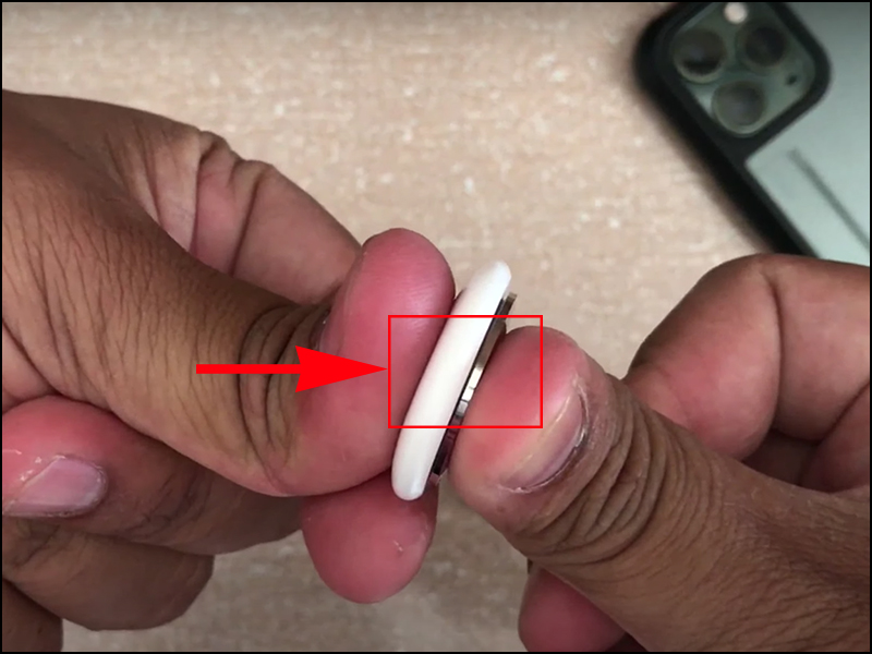 Ấn v&agrave; xoay ngược chiều kim đồng hồ để th&aacute;o nắp AirTag